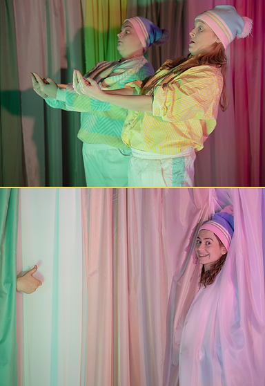 Skådespelare i färgade ljus, delvis dold bakom tyg.