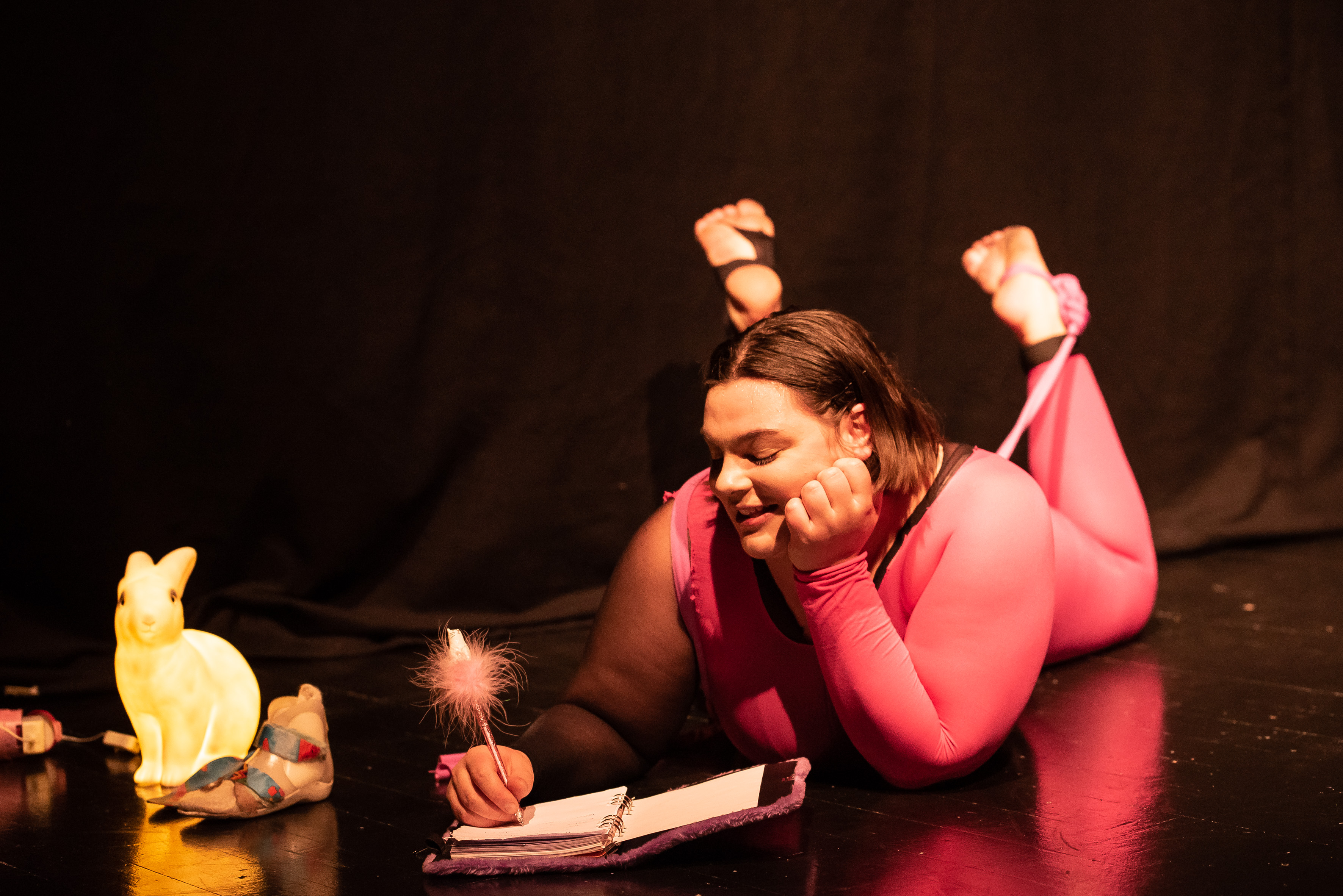 Linnea Sundblom ligger på scenen och skriver i ett block.